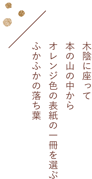 禾陰に座って本の山の中からオレンジ色の表紙の一冊を選ぶふかふかの落ち葉