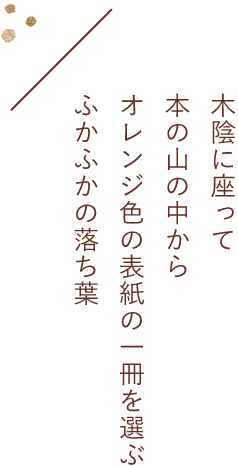 禾陰に座って本の山の中からオレンジ色の表紙の一冊を選ぶふかふかの落ち葉